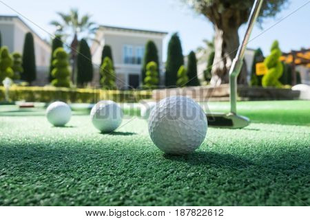 Mini golf scene with ball and club. Sunny day at resort park