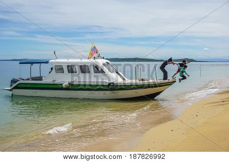 Labuan,Malaysia-Feb 19,2017:Kids jumping off the boat into a beautiful sandy beach of Papan island in Labuan,Malaysia.Having fun on a summer vacation at the beach with friends
