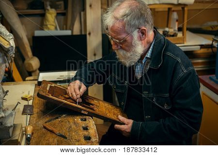 Senior wood carving professional during work