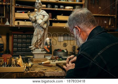 Senior wood carving professional during work