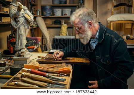 Senior wood carving professional during work