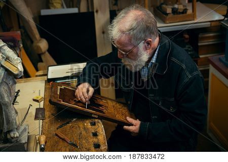 Senior wood carving professional during work