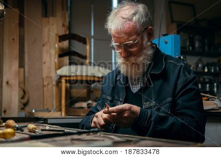 Senior wood carving professional during work