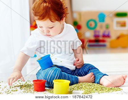 Cute Redhead Baby Boy Developing His Fine Motility Skills By Playing With Green Peas At Home