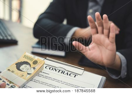 Businessman refusing money South Korean won that come with contract paper - anti bribery and corruption concepts