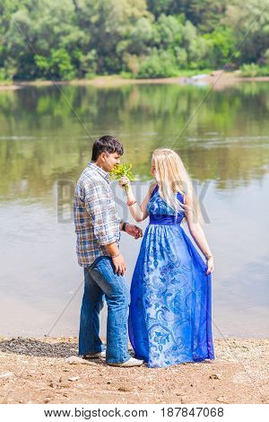 Young happy couple having fun beside river in summer sunny day