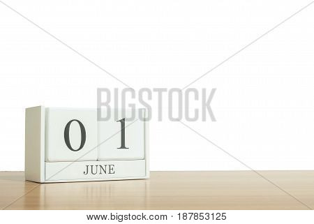 Closeup surface white wooden calendar with black 1 june word on blurred brown wood desk isolated on white background with copy space selective focus at the calendar