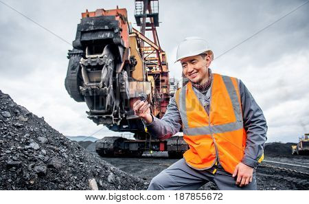 coal mining worker with rotary excavator on the background