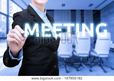 Business women writing Meeting word with blur meeting room and conference room in background.Photo for business corporation and teamwork concept