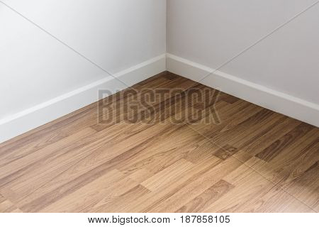Laminated wood floor with white wall, room's corner