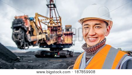 coal mining worker with rotary excavator on the background