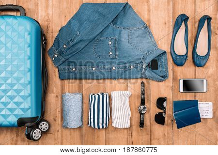 Flay lay of business holiday concept with clothes smartphone passport and tickets on wooden floor.