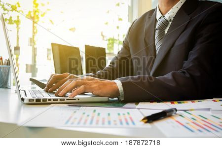 Close up of hand of business man working document and laptop in office morning light. business concept.