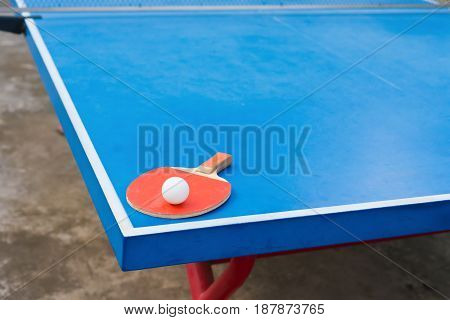pingpong racket and ball on a blue pingpong table
