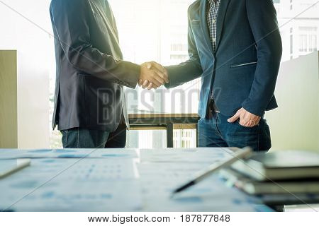 Two businessmen shaking hands during a meeting in the office success dealing greeting & business partner.