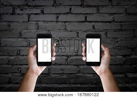 Man's hands holding blank screen of a smartphone at the old black brick wall.