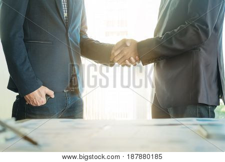 Two confident business man shaking hands during after a meeting in the office success dealing greeting and partner concept.