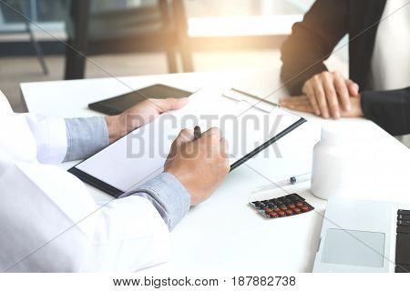 Healthcare and Medical concept patient listening intently to a female doctor explaining patient symptoms or asking a question as they discuss paperwork together in a consultation.