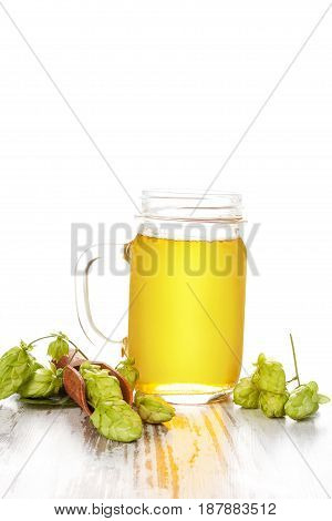 Beer lemonade in glass with hop in scoop on white wooden table. Shandy drink Radler.