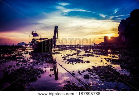 traditional long tail boat silhouette at low tide in sunset liights on Ton Sai beach, Thailand