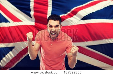 emotion, aggression, patriotism, gesture and people concept - angry young man showing fists and shouting over brittish flag