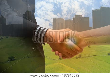 Double exposure of handshake with blur city and agriculture concept with the fake flarethe partnership between business man and farmer