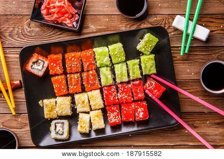 Sushi Set rolls with soy sauce served on black plate on wooden background