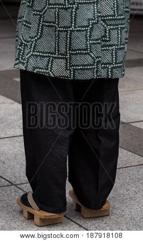 Asian man wearing traditional japanese wooden sandals Geta footwear and tabi socks on the streets of Tokyo, Japan