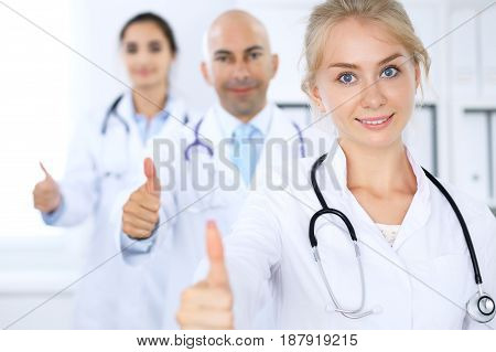 Happy doctor woman with medical staff at the hospital. Thumbs up