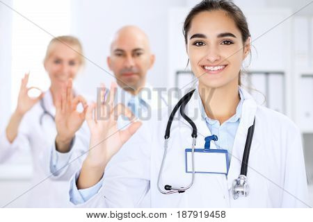 Happy doctor woman with medical staff at the hospital. Thumbs up and Ok sign
