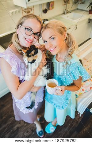 two happy women arm in arm in the kitchen dressed in aprons