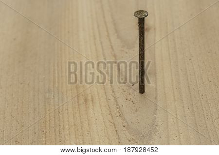 single nail being driven into a board