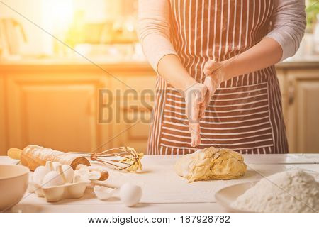 Woman slap his hands above dough closeup. Baker finishing his bakery, shake flour from his hands, free space for text. Homemade bakery, cooking process concept