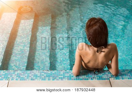 Beautiful woman relaxing at the luxury poolside. Girl at travel spa resort pool. Summer luxury vacation.