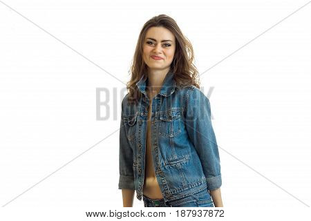 smiling beautiful brunette stands in jeans jacket and looks into a camera isolated on white background