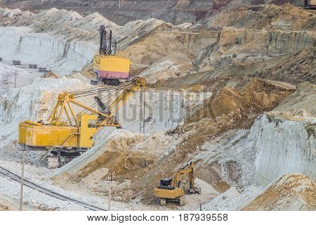 Work of heavy mining excavators in the chalky quarry. Heavy chalk mining industry.