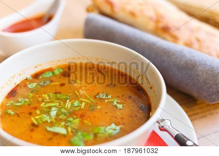 Soup kharcho sprinkled with fresh herbs. Traditional Georgian soup Kharcho with meat and rice on old wooden background. Selective focus.
