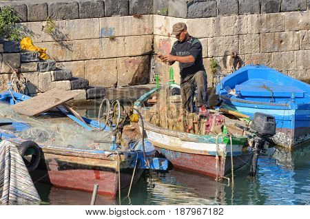 Fisherman tries to untangle his net in the port - Siracusa Sicily Italy, 17 October 2011