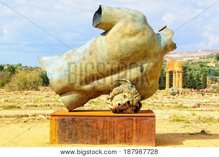 Back and head of Igor Mitoraj`s bronze sculpture, Torso di Ikaro, and the Temple of Castor and Pollux - Agrigento, Sicily, Italy, 19 October 2011