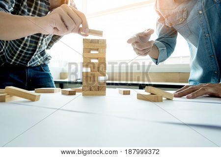 Hand Of Engineer Playing A Blocks Wood Tower Game (jenga) On Blueprint Or Architectural Project.