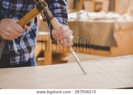 Carpenter Working With Chisel And Hammer On Wood. Workshop Background. Carpenter Workbench.