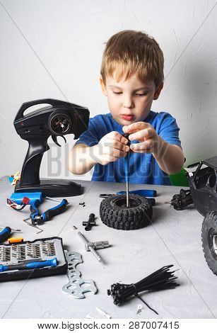Radio Controlled Models: A Little Boy In A Blue T-shirt Is Repairing His Rs Car Buggy.