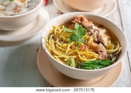 Asian soup noodles and chicken in bowl on wooden background. 