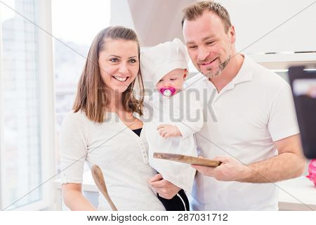 Happy Parents Standing In The Kitchen With Their Baby Girl Chef
