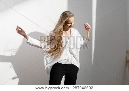 Beautiful Thoughtful Model Looking Down In White Shirt And Black Trousers On White Background