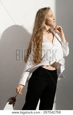 Beautiful Fresh Blonde Model In White Shirt And Black Trousers With Flower In Hand