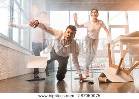 Scared Businessman Falling On Floor While Running And Screaming Near Coworkers In Office With Smoke