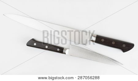 Two kitchen knives on light gray background shot from above