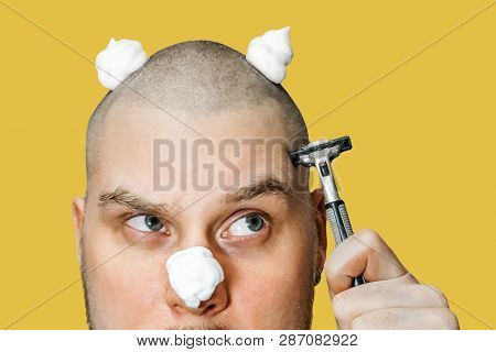 A Guy With A Beard And A Razor In His Hand, With Foam And Gel On His Face Shaves In The Morning At H