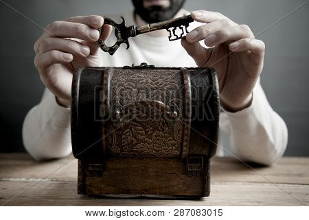 Man Hand Holding Key And Wooden Box